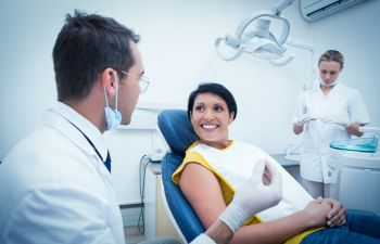 woman in a dental chair talking to a dentist