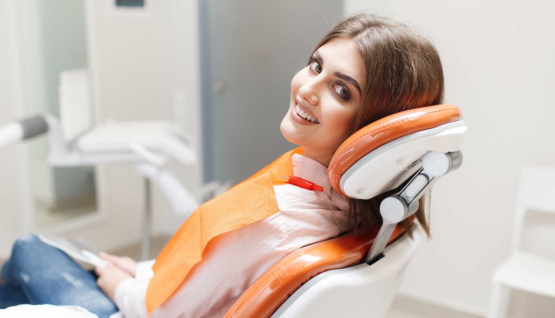 happy young woman in a dental chair after dental checkup and cleaning