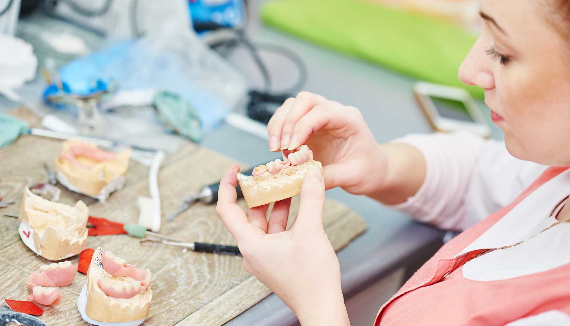 Dental technician working with tooth dentures at prosthesis laboratory