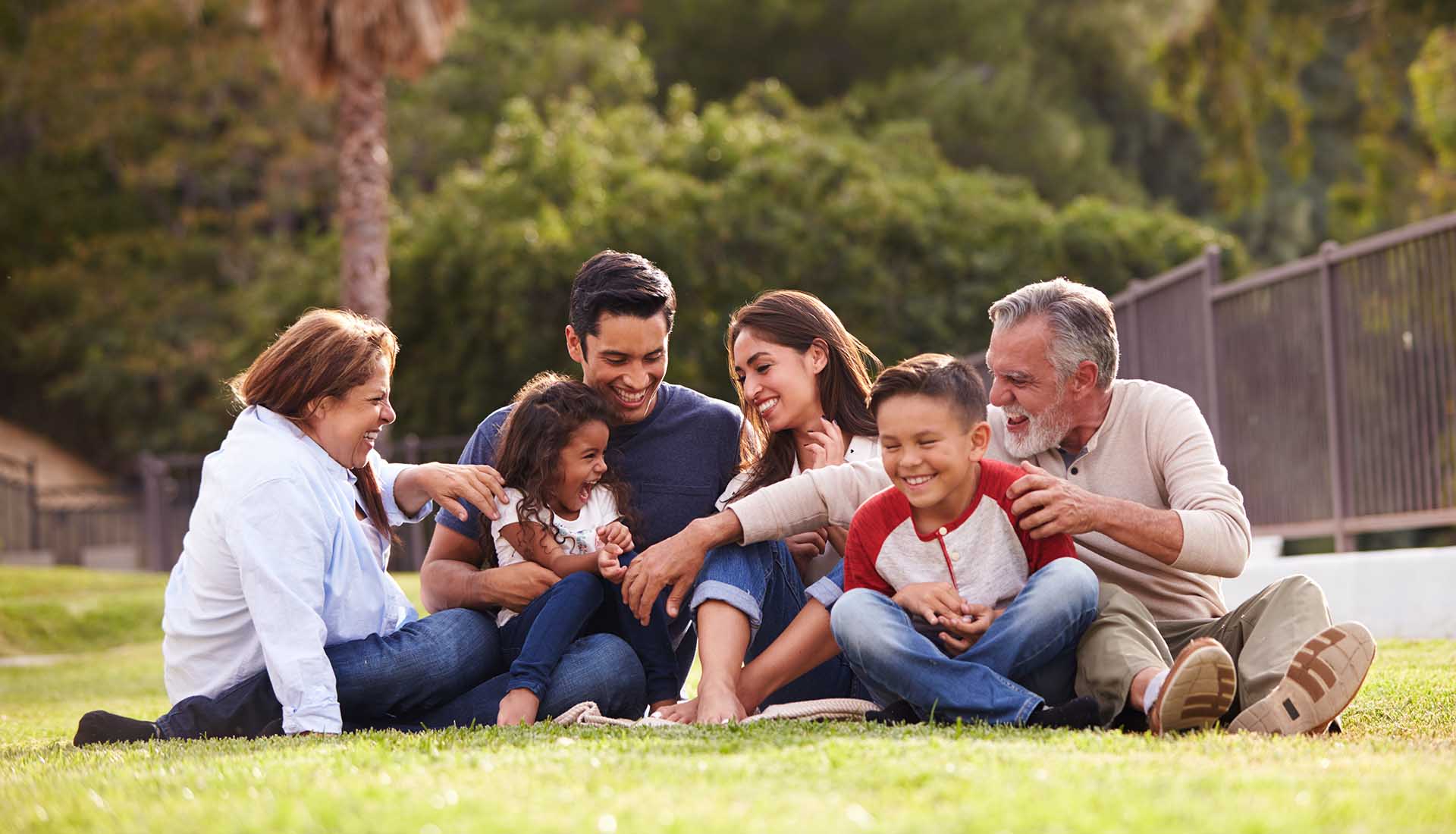 Happy three generation Hispanic family sitting having picnic