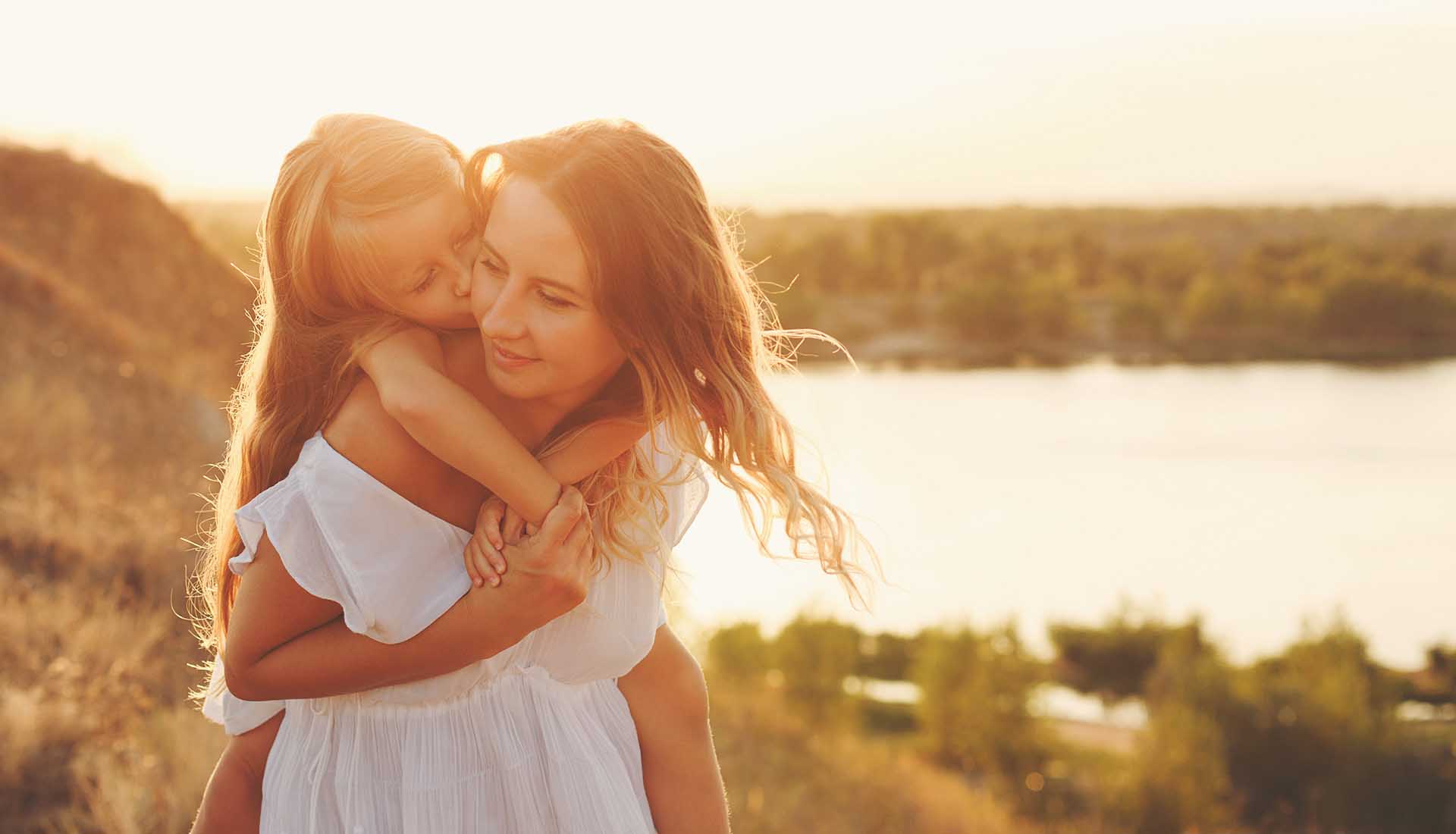 happy mother spending time with her little daughter by lake