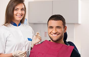 Happy male patient and smiling female dentist at dental surgery.