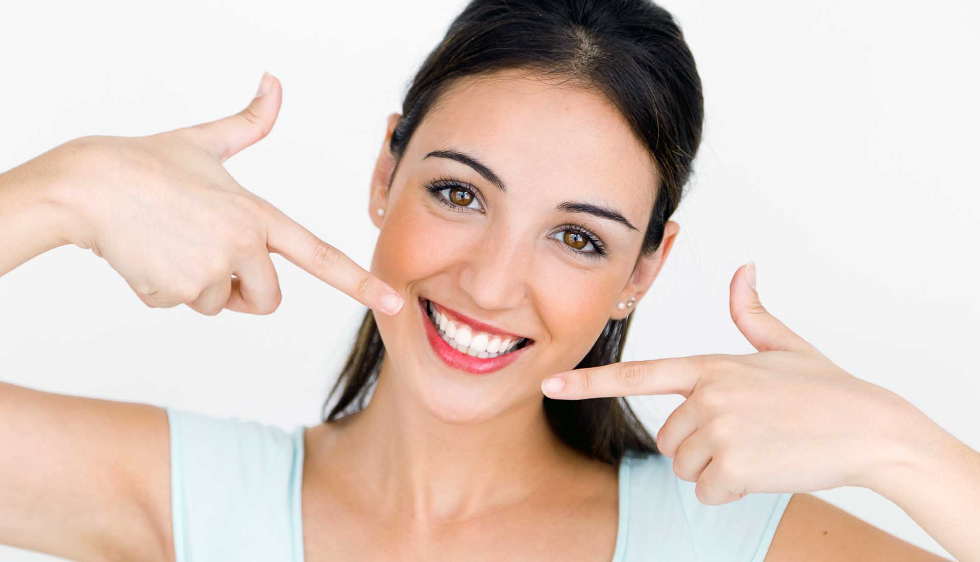 smiling young woman pointing at her perfect teeth