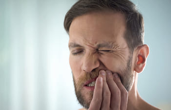 man with dental pain caused by gum disease