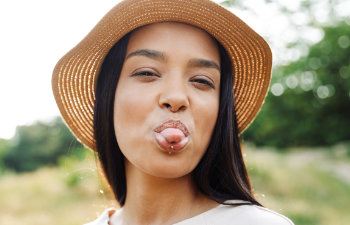 girl with lip piercing and hat stick out her tongue